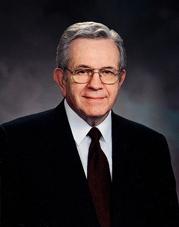 A portrait of President Boyd K. Packer, who is wearing a black suit and a maroon tie, in front of a gray background.