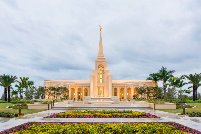 The front of the Fort Lauderdale Florida Temple in the early evening just as the lights have come on, with the fountains running near the entrance.