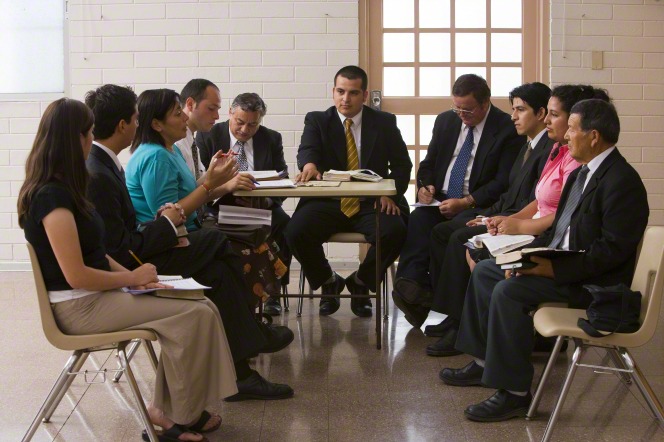 Ten ward council members sit in plastic chairs, discussing issues and taking notes.