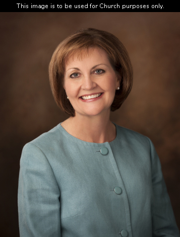 A portrait of Sister Linda K. Burton, who is wearing a turquoise jacket, in front of a brown background.
