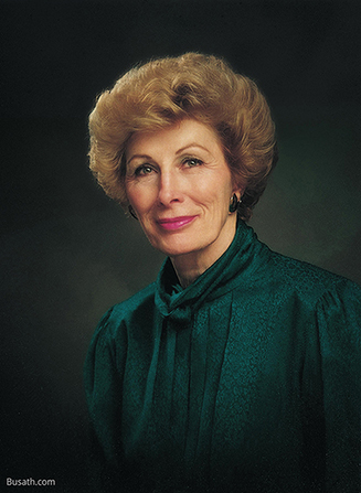 A photograph of Elaine Low Jack against a gray background, wearing a dark green blouse.
