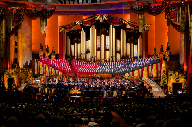 A view of the audience watching the Mormon Tabernacle Choir and orchestra, who are bordered by red curtains at the 2012 Christmas concert.
