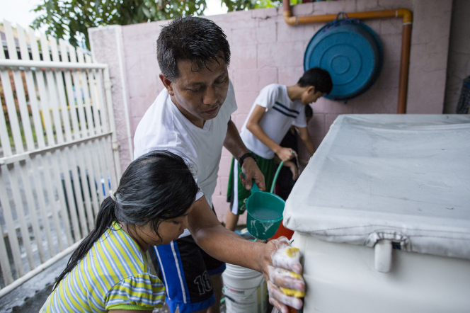 A man and his daughter and two sons work together to scrub a white truck.