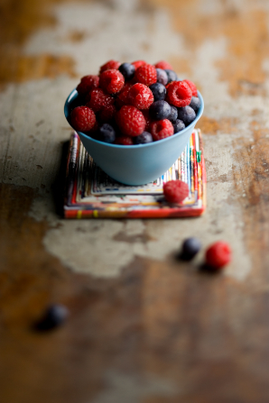 Blueberries and raspberries in a little blue bowl.
