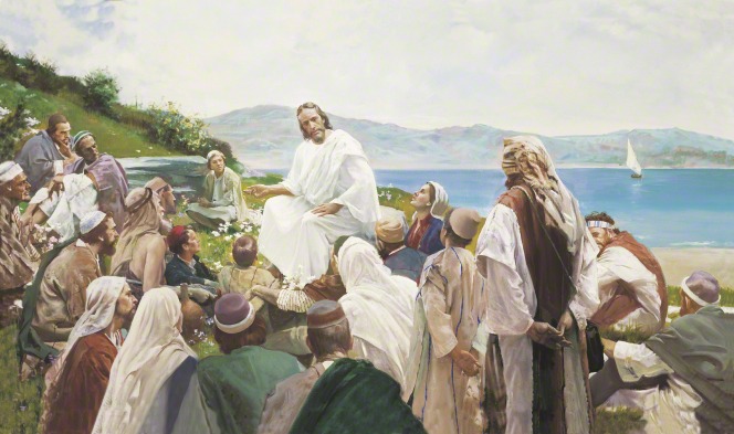 Jesus in white robes, sitting on a hillside by the sea, surrounded by a large group of people who are listening to His teachings.