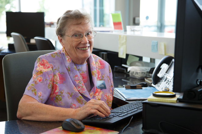 A sister missionary smiles as she works on a computer in the office of a bishops’ storehouse.