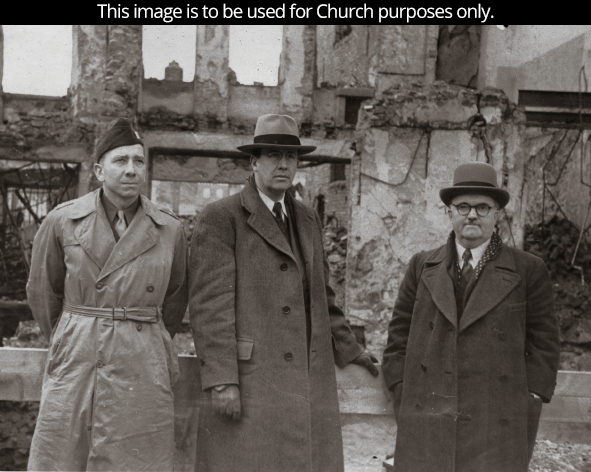 Elder Benson around 1946, standing with two missionary companions in long coats and hats in Europe.