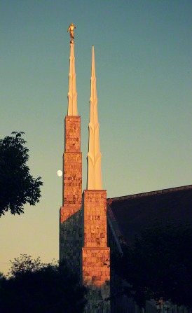 The spires of the Boise Idaho Temple in the late evening, with the moon rising in the background.